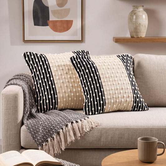 Grafische Kissenhülle Mono Rhythm in Schwarz und Natur auf einem hellen Sofa